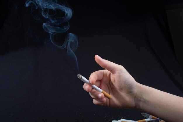 Hand is holding smoking cigarette on black background