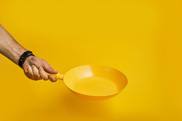 A hand is holding a yellow pan on yellow