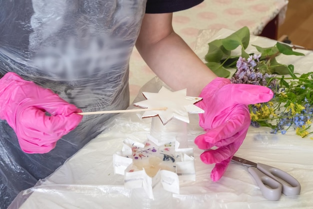 Hand is in motion selective focus Art process of pouring epoxy resin into a wooden toy Technology process of creating a painting in style resin art works with epoxy in studio makes a wooden stand