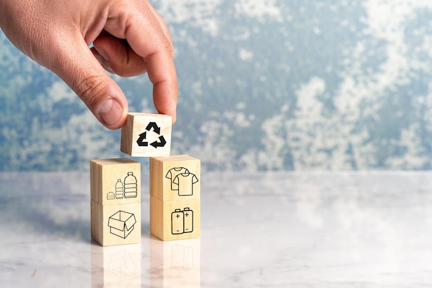 A hand is placing a recycle symbols on a wooden block