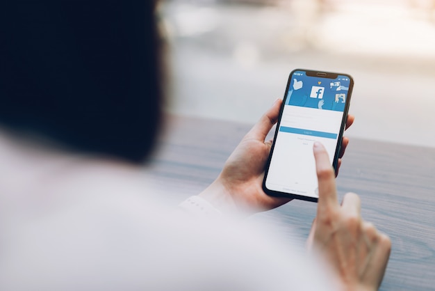 hand is pressing the Facebook screen on smartphone