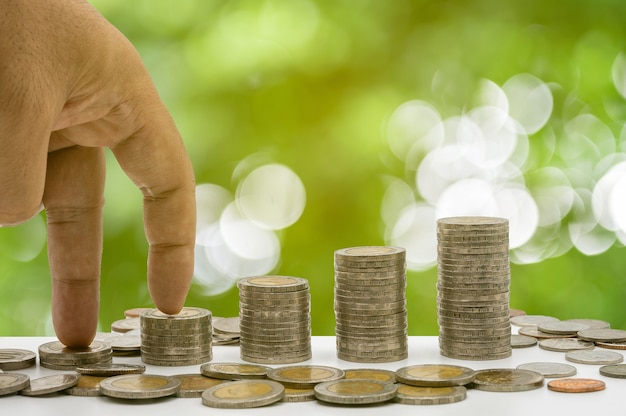 The hand is stepping on coins stacked and coins accummulate in column that represent money saving or financial planning idea for economy.