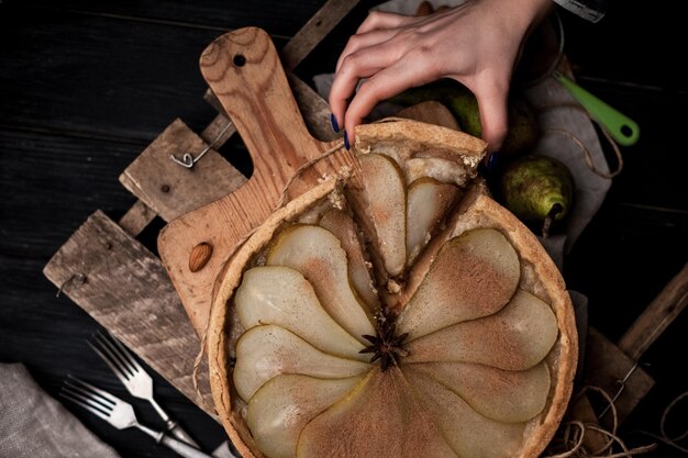 The hand is taking a piece of homemade pear tart with cinnamon and sugar. Selective focus.