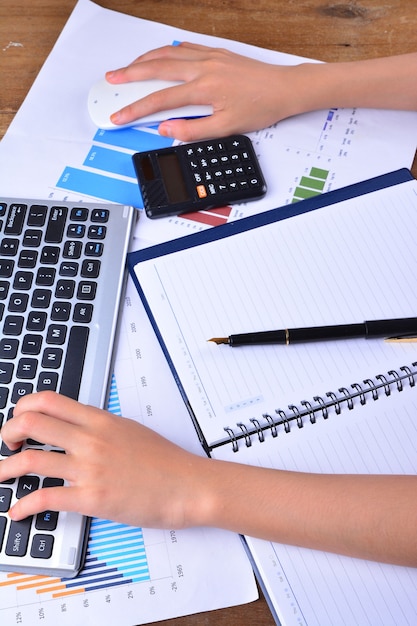 Hand on keyboard and mouse with graph, chart on wooden table