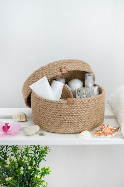 Hand knitted jute basket with a lid with accessories and cosmetics in the bathroom on a white wooden rack with copy space