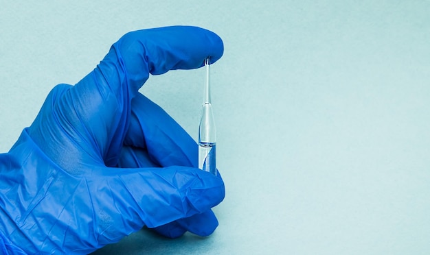 Hand of a lab technician or medical doctor holding ampoule close up