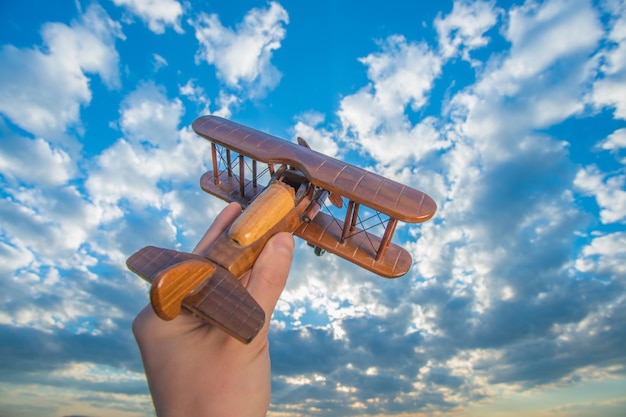 The hand launch wooden plane on the background of a blue sky