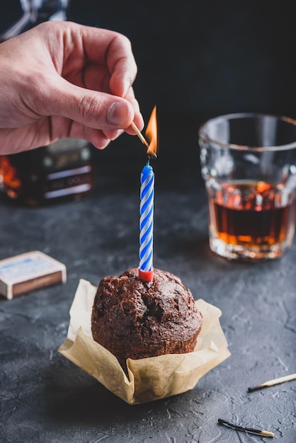 Hand lighting candle on birthday muffin