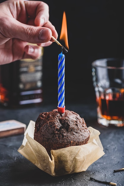 Hand lighting candle with a match on birthday chocolate muffin