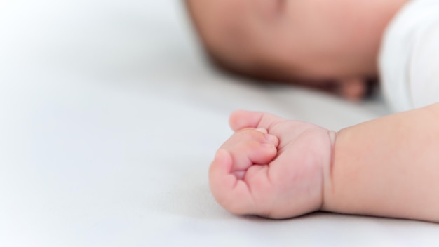 Hand of little baby on white sheet bed background Cute boy and chubby hands