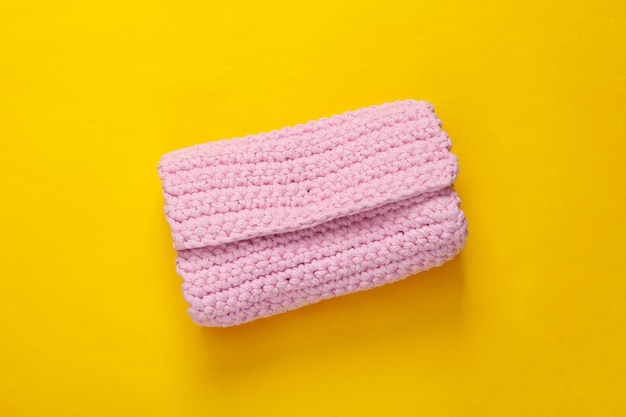 Hand made knitted pink wallet on yellow background