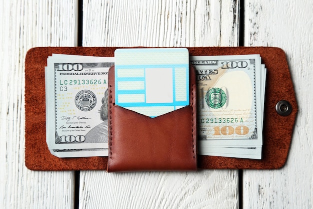 Hand made leather man wallet with money on white wooden background