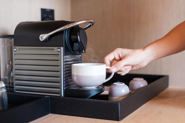 Hand making Espresso by Coffee Machine with capsules on wood table