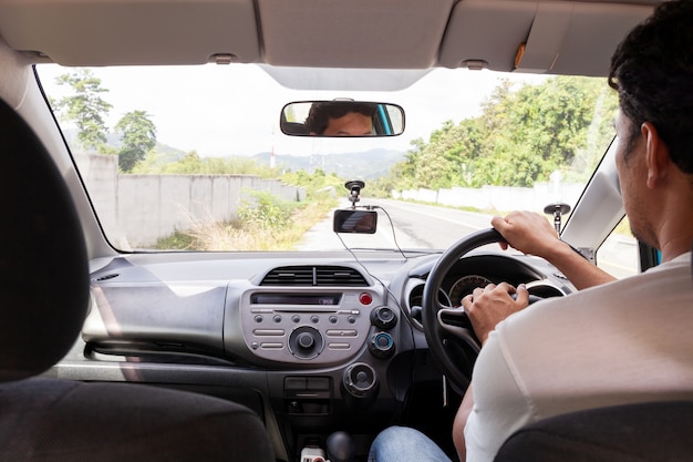 Hand male holding the steering wheel to drive the car on asphalt road.