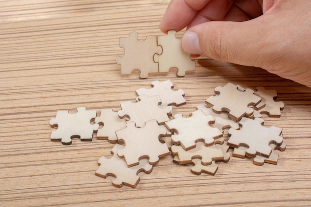 Hand of male trying to connect pieces of jigsaw puzzle