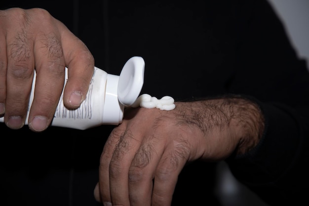 Hand of a man applying cream lotion on arms to protect