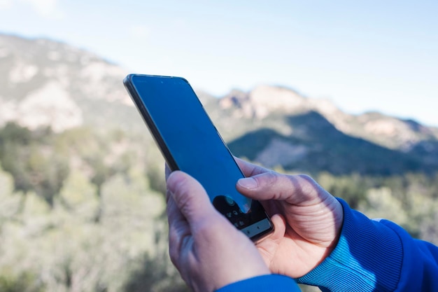 The hand of a man travel in nature holds a smartphone