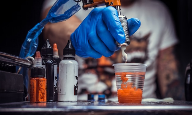 Hand of a master of the art of tattooing and a tattoo gun