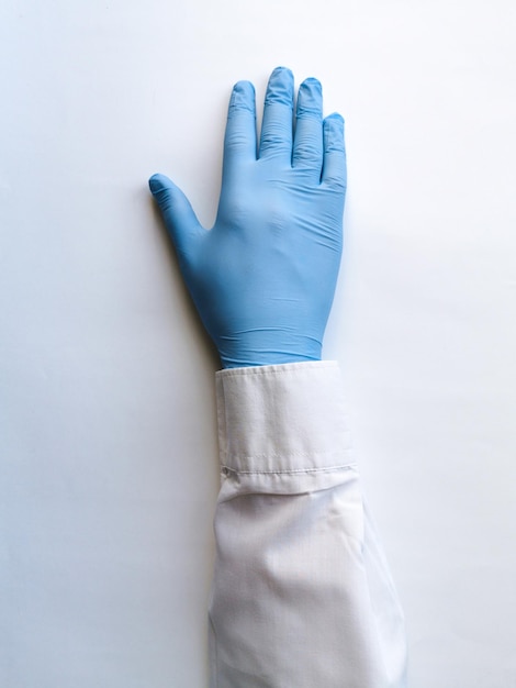 The hand of a medical worker in a blue glove lies on a white table