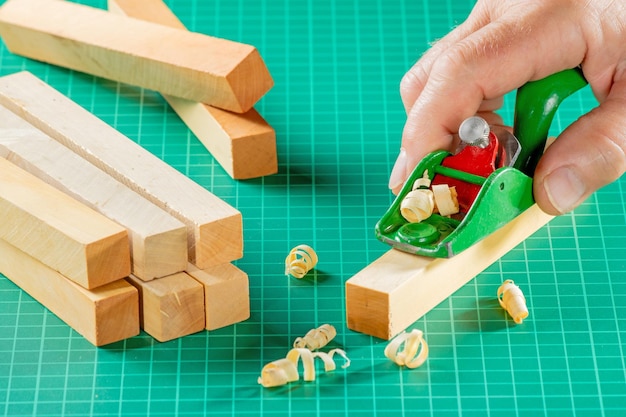 The hand of a modeler is cutting a block of boxwood with a miniplaner