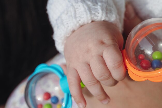 Hand of a newborn baby with a toy. Plastic toy for a child