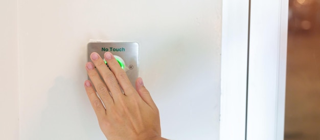 Hand open the door by No touch sensor switch on the wall at office or apartment Contactless modern Technology and safety concept