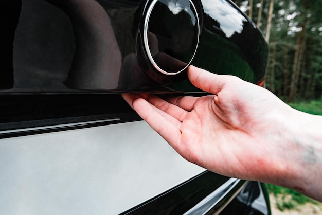 Hand opening the back door of the black car.