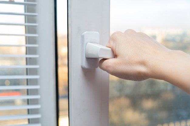 Hand opening a plastic window to air the room for fresh air in spring and summer, sunny day