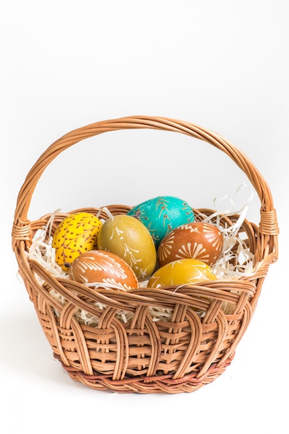 Hand-paited easter eggs in brown basket on white