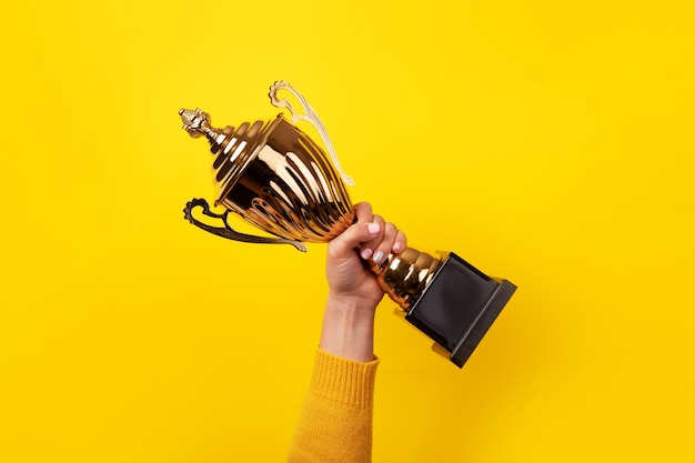 Hand of the person with a sports cup over yellow background