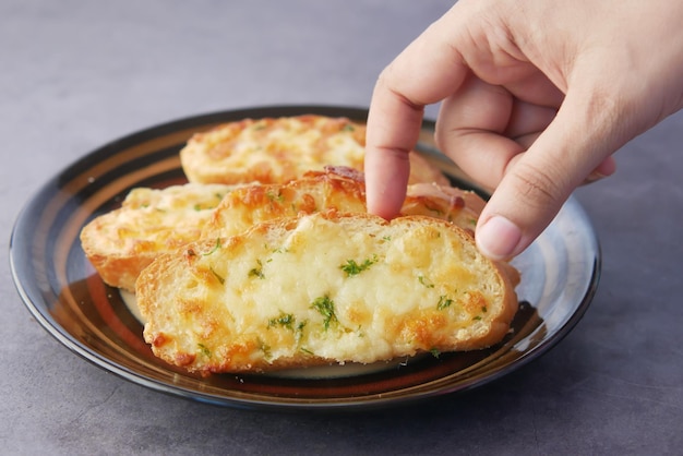 Hand pick a garlic bread on a plate