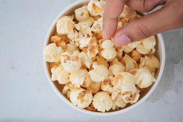 Hand pick popcorn in a bowl on table