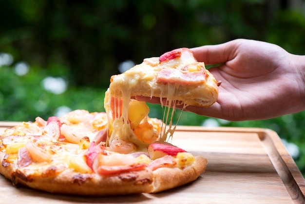 Hand picked pepperoni pizza on Wooden cutting board