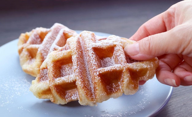 Hand Picking a Croffle or Croissant Waffle Sprinkled with Powdered Sugar