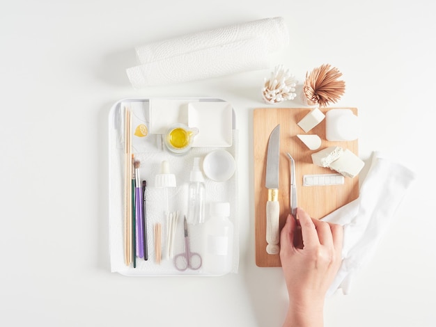 hand picking up tweezers from a tray with various tools and utensils to prepare food for a photo sho