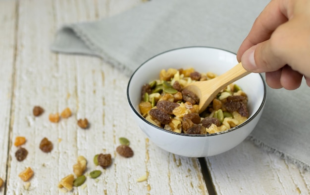 Hand picking up wooden spoon in bowl full of dried fruit pieces