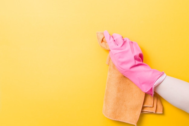 Hand in a pink rubber glove holds an orange rag for washing and cleaning