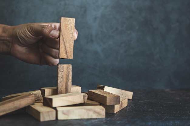 Hand place wooden block stacked concept of prevent collapse