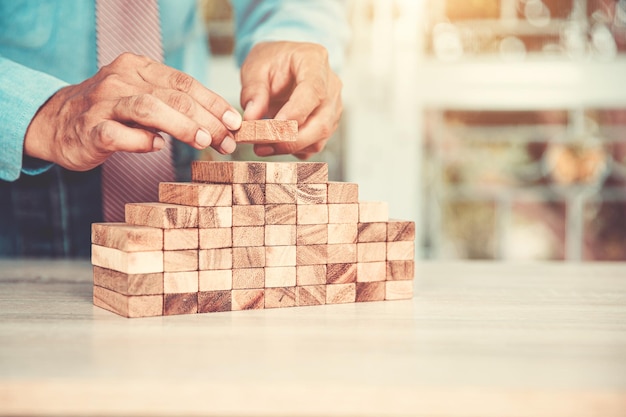 Hand placing wood block tower stack in pyramid stair step