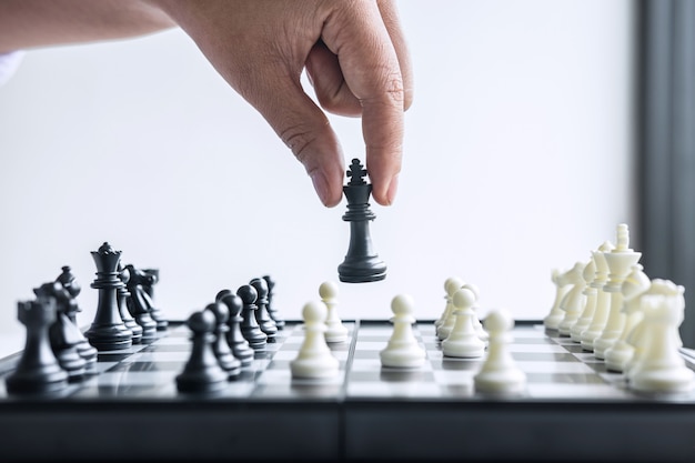 Hand playing chess with black and white pawns