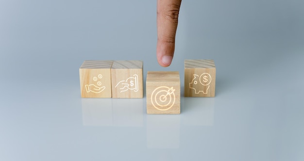 Hand pointing at one wood cube block with target icon Concept of business strategy.