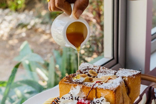 Hand pouring honey on Honey toast