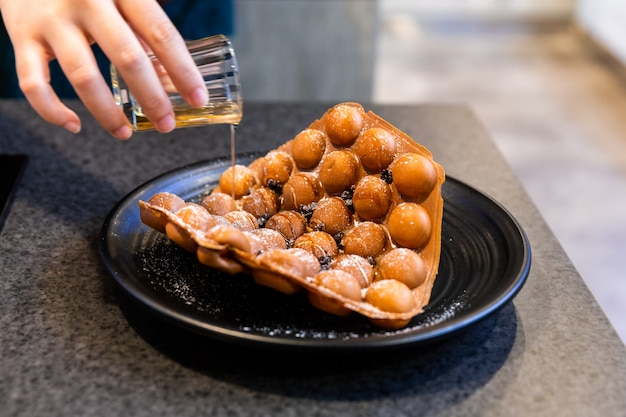 Hand pouring syrup on Hong Kong Waffle.