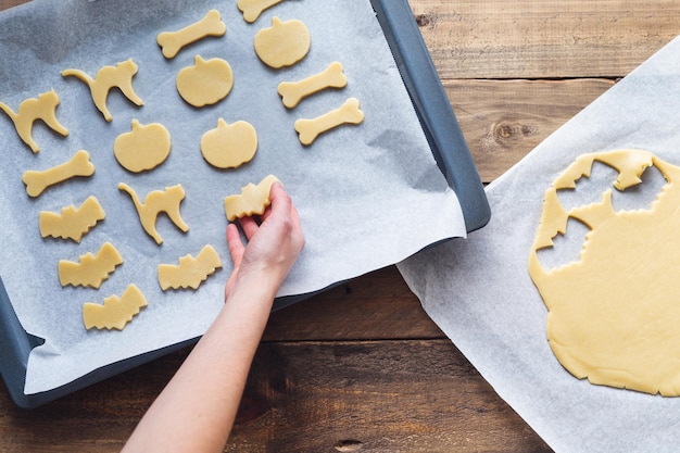 Hand preparing cookies in different shapes for Halloween Copy space