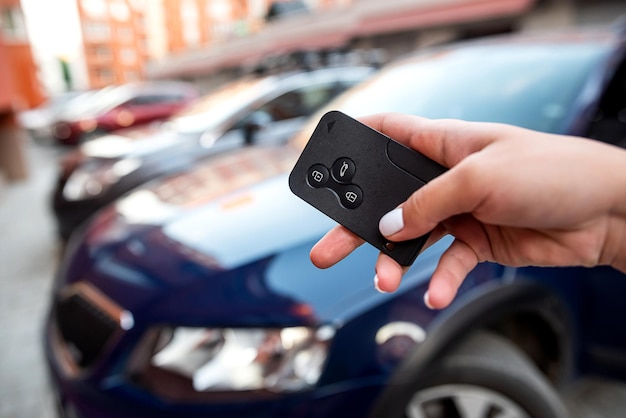 Hand presses the car alarm control panel in front of his own new car