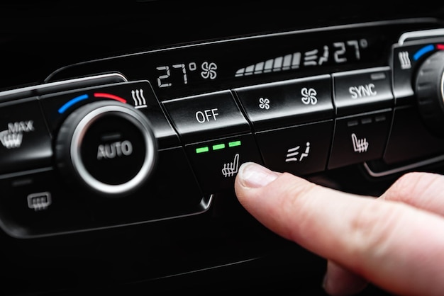 Hand pressing the button for heated seats in the car