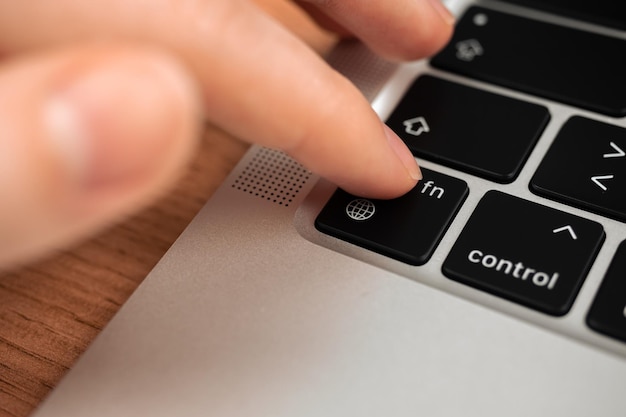 Photo hand pressing the globe key on modern laptop keyboard the globe sign and symbol closeup