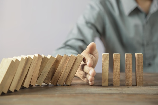 Hand prevent wooden block tower stack crash or fall domino concept of prevention of financial business and risk management or strategic planning