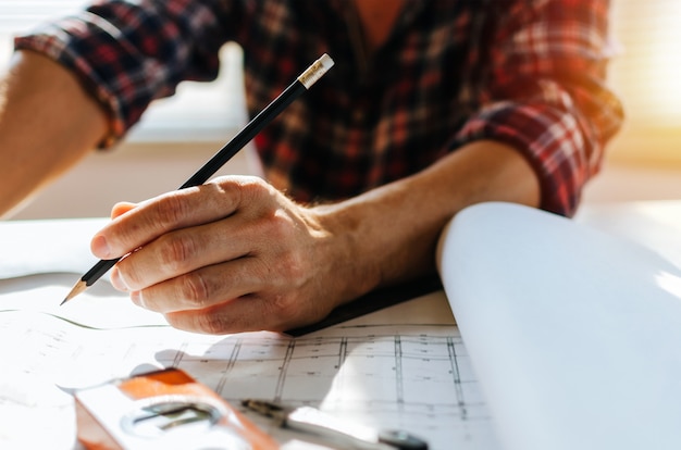 Hand professional architect, engineer or interior hands drawing with blueprint on workplace desk 