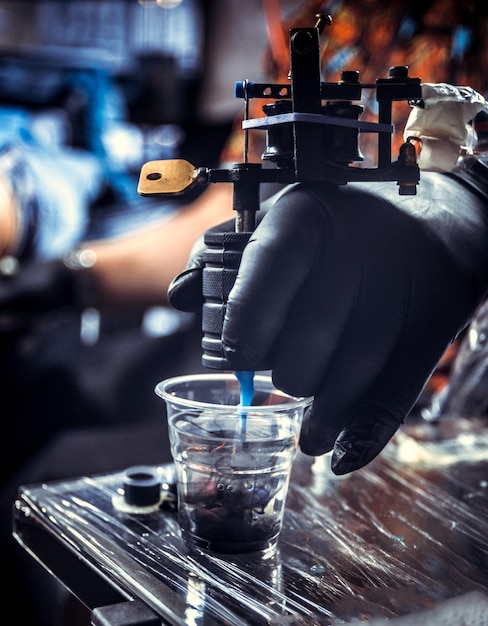 Hand of professional tattooist and a tattoo machine